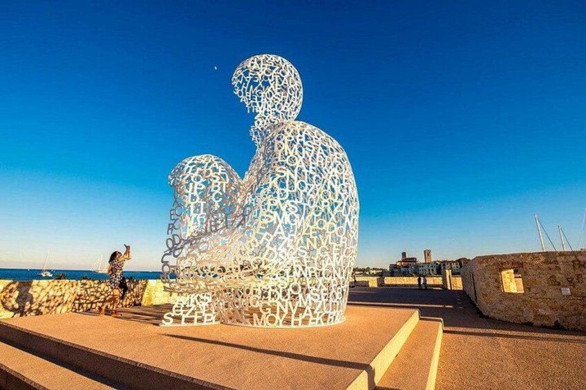 A large metallic sculpture of a seated figure on a beach. 2