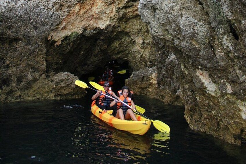 A person kayaking through a narrow water passage surrounded by rocky cliffs. 2