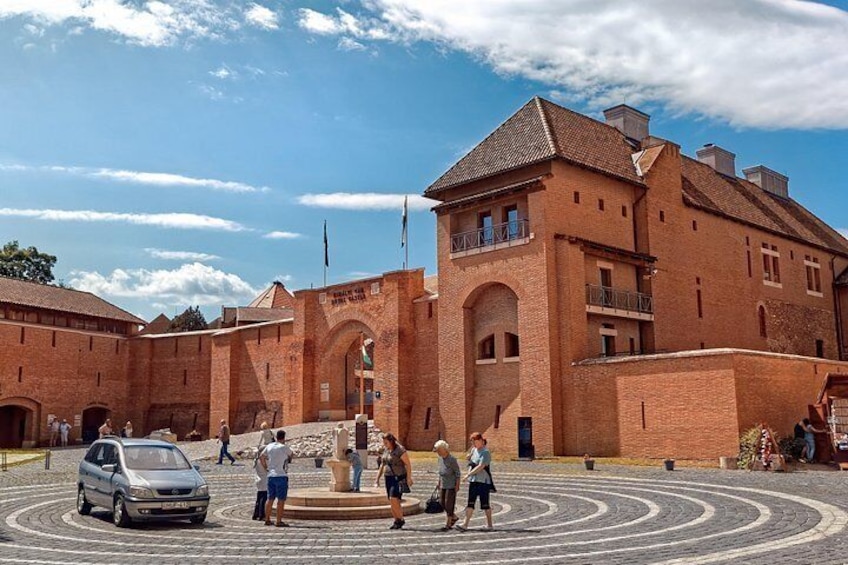 A historic brick building with a circular courtyard, a fountain, and people walking around. 3