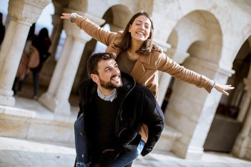 A person being carried on another's back, with stone arches in the background. 2