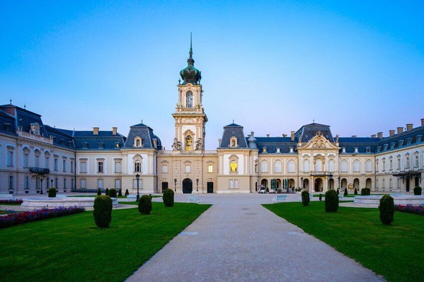 A grand historical building with a central tower, symmetrical wings, and a well-maintained lawn. 5