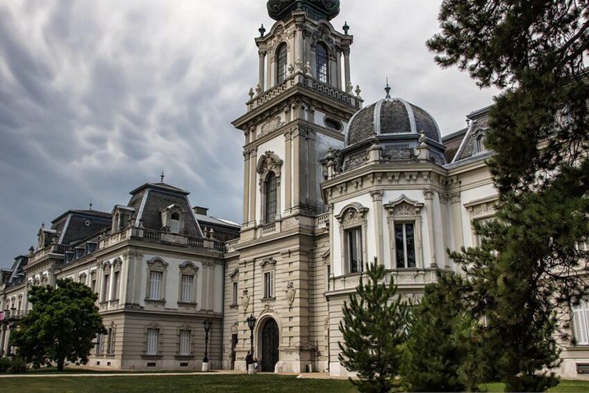 A historic building with a prominent tower and dome, surrounded by trees and a well-maintained lawn. 4