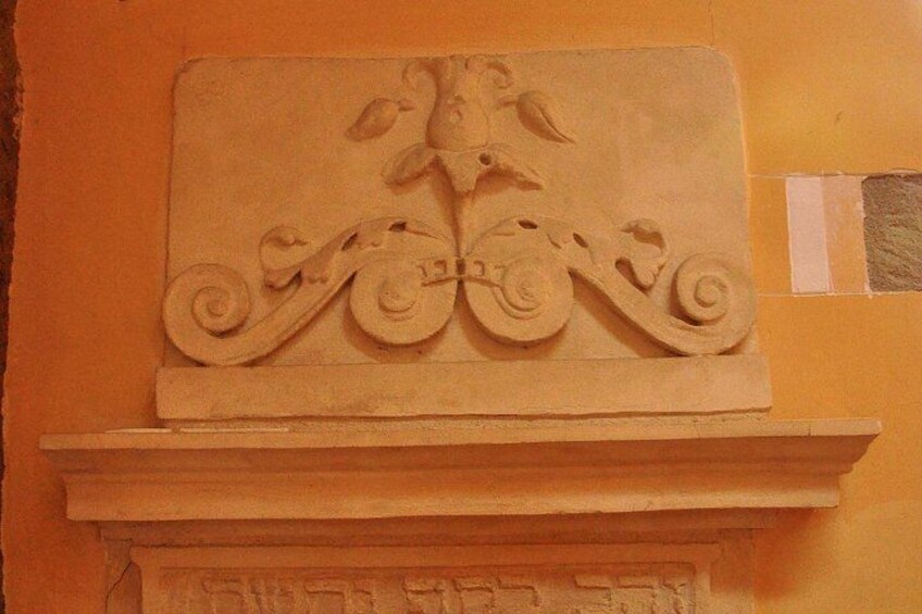 A carved stone relief with floral and scroll motifs on a wall. 3