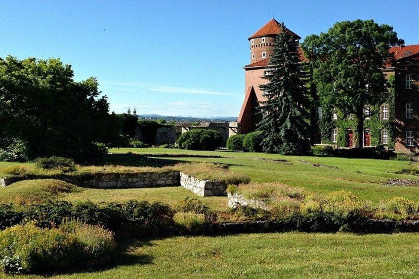 A historic building with a tower, surrounded by a well-maintained grassy area with stone walls and trees. 5