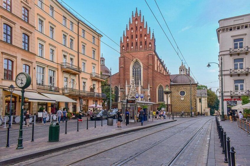 A street with a tram, a church, and buildings with shops. 4