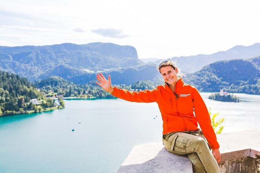 Una persona con chaleco naranja sentada en un saliente con vista a un lago y montañas al fondo. 2