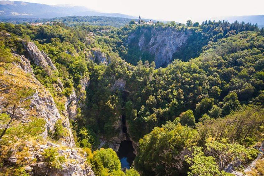 A canyon with dense forest, rocky cliffs, and a small building on top. 3