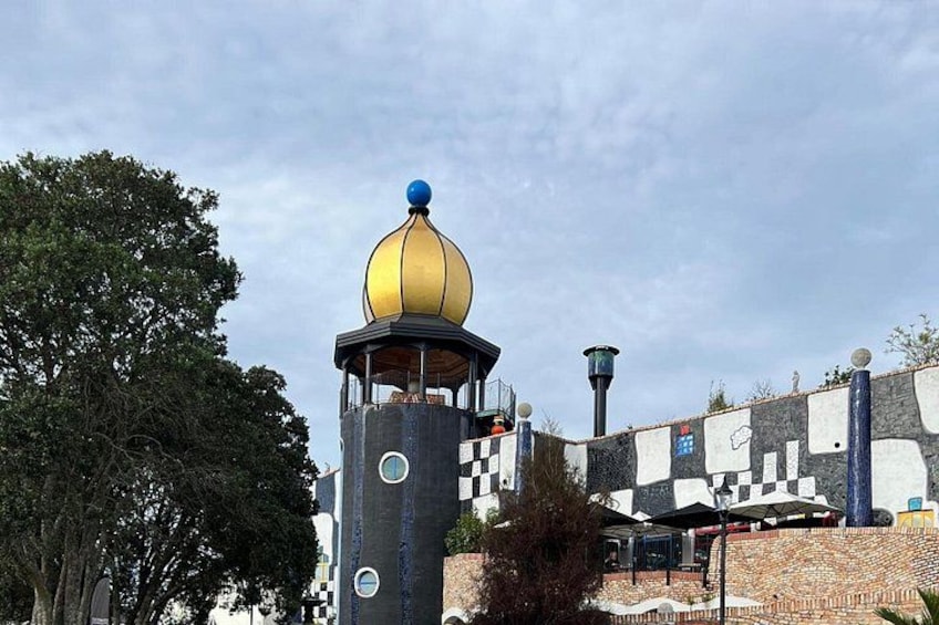 Una torre con una cupola dorata, un muro decorato e un albero. 3