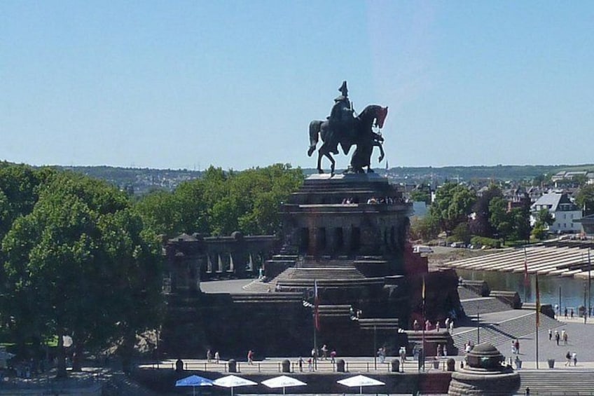 A statue on a pedestal, a large open plaza, and a distant view of a cityscape. 3