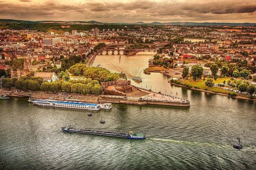 A river with boats, a bridge, and a cityscape with buildings and greenery. 1