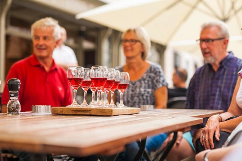 A group of people seated at a table with wine glasses and a wooden board. 1