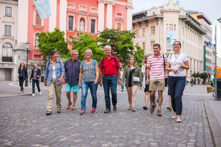 A group of people walking on a cobblestone street in an urban area with historic buildings in the background. 3