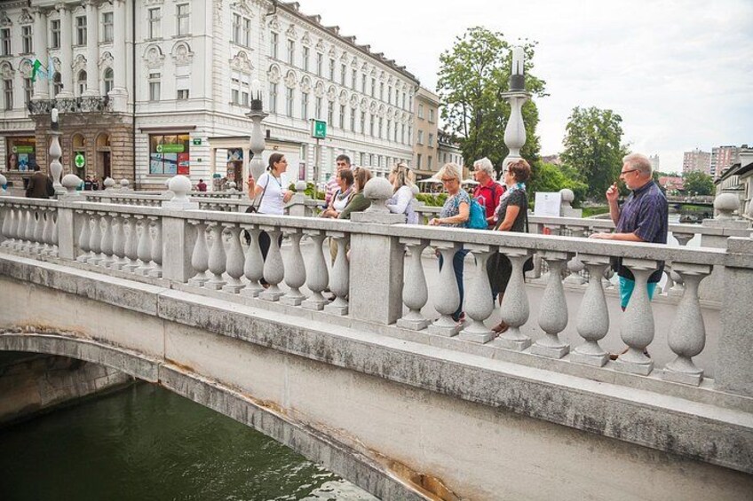 A stone bridge with balustrades, a waterway beneath, and buildings in the background. 5