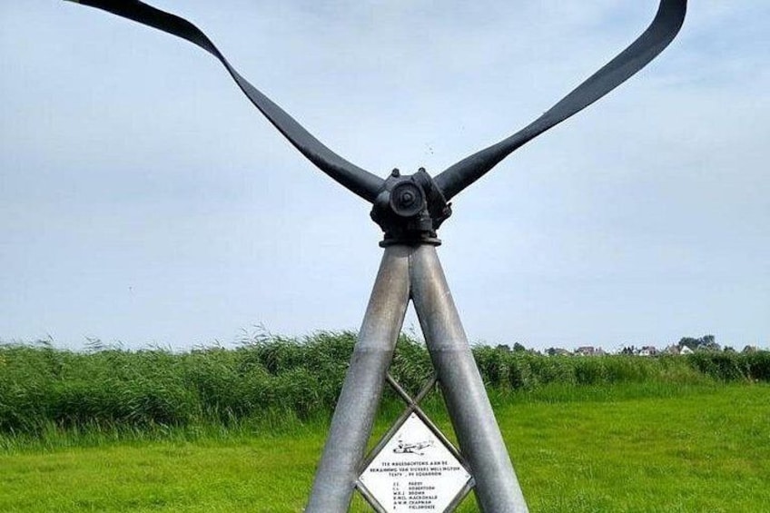 En vindmølle med tre blade, en metalstruktur og et skilt med tekst. 4