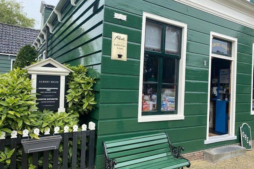 A green building with a signboard, a bench, and a small garden area. 2