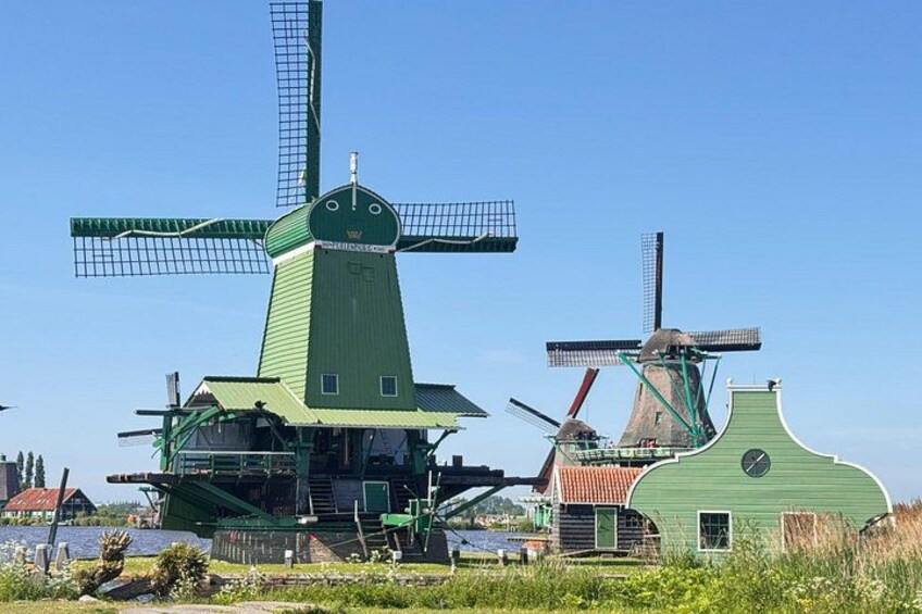 Two windmills with green roofs and white walls, surrounded by greenery and a clear sky. 2