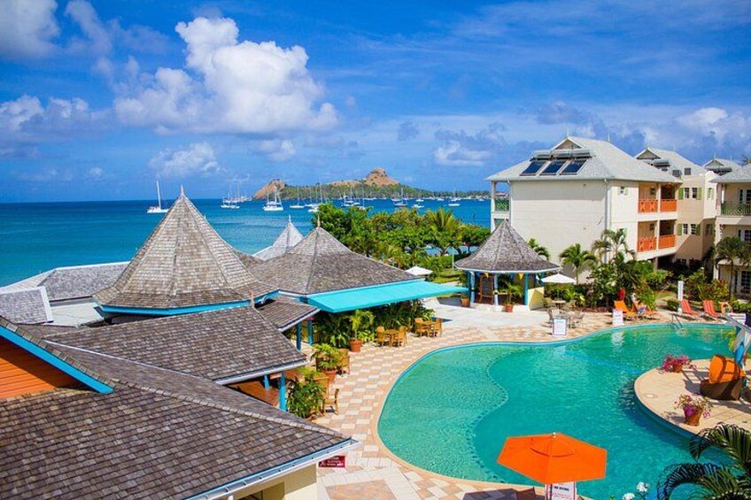 A resort with a swimming pool, beach umbrellas, and a view of the ocean. 3