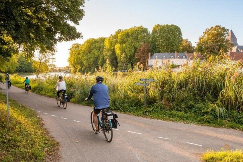 Ein gepflasterter Weg mit Radfahrern, umgeben von Grünpflanzen und einem Gebäude im Hintergrund. 5