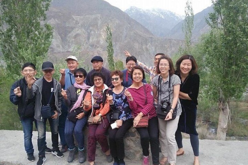 A group of people posing in a mountainous area with trees and a rocky landscape. 2