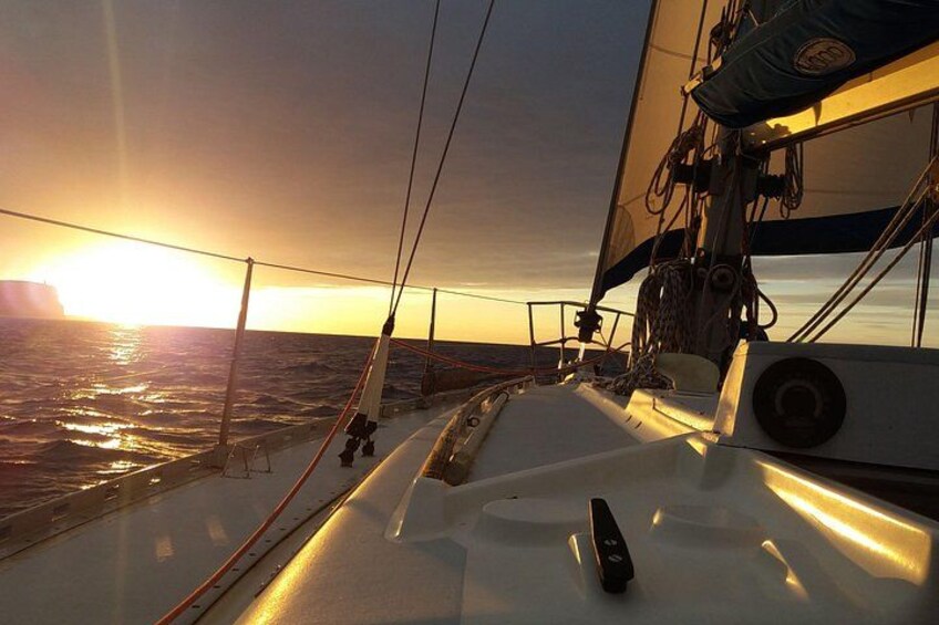 Dækket på en sejlbåd med udsigt til havet og en solnedgang. 2