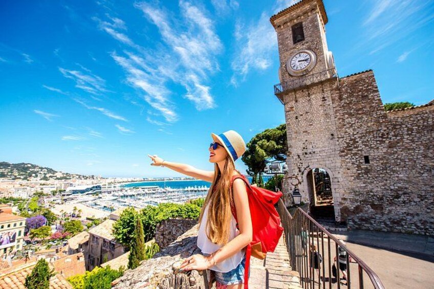 A person standing on a stone wall overlooking a coastal town with a clock tower. 4