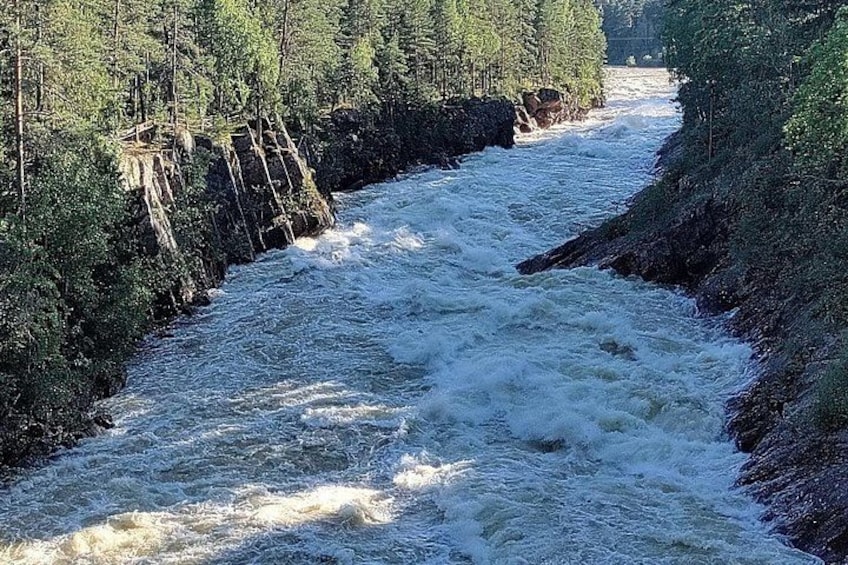 A river flowing through a forested area with rocky banks and a wooden structure on the left. 3