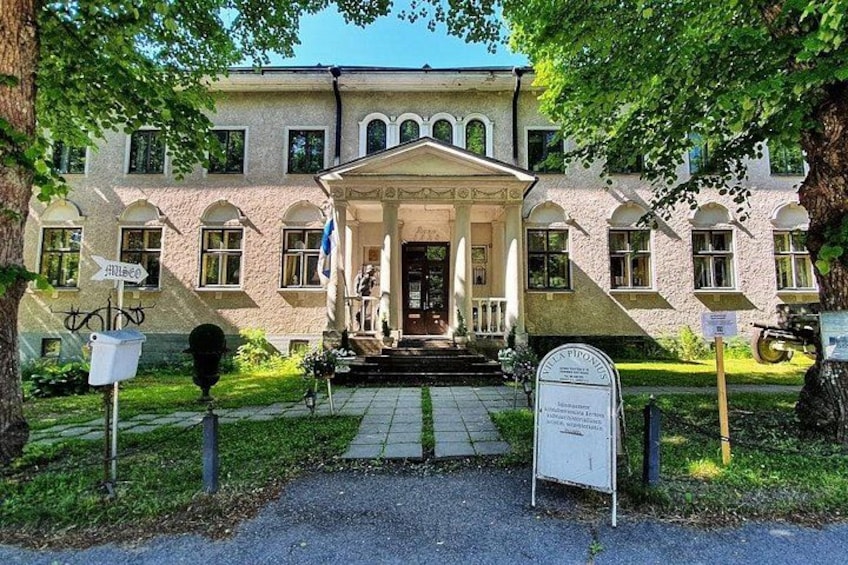 A historic building with a central entrance, a signboard, and a bicycle parked nearby. 1