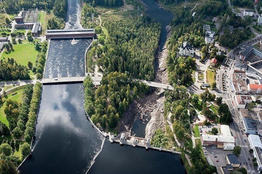 A river with a dam, surrounded by greenery and urban buildings. 5