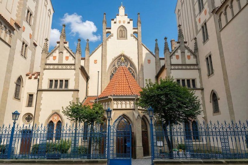 Un edificio histórico con techo de tejas rojas, ventanas arqueadas y valla de hierro azul. 5