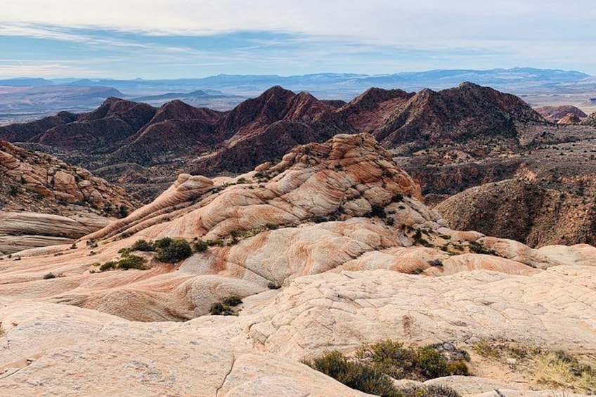 A rugged mountainous landscape with layered rock formations and distant hills. 3