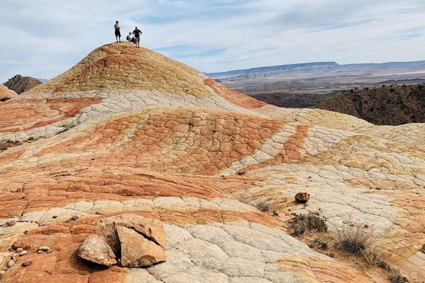 A rugged, layered rock formation with people standing on top. 1