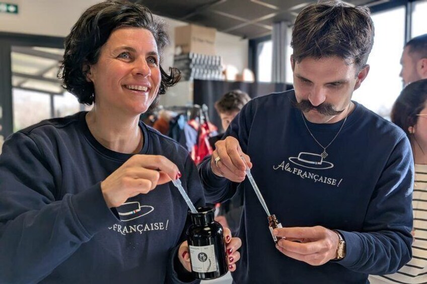 Two people wearing matching 'Ala. FRANCAISE!' sweatshirts, holding and tasting a bottle of wine. 5