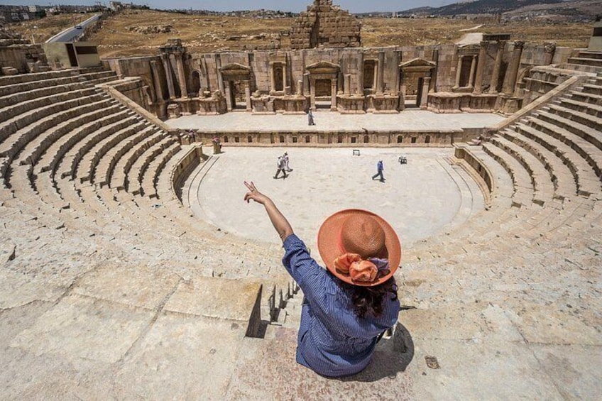 An ancient amphitheater with stone seating and a central stage. 1