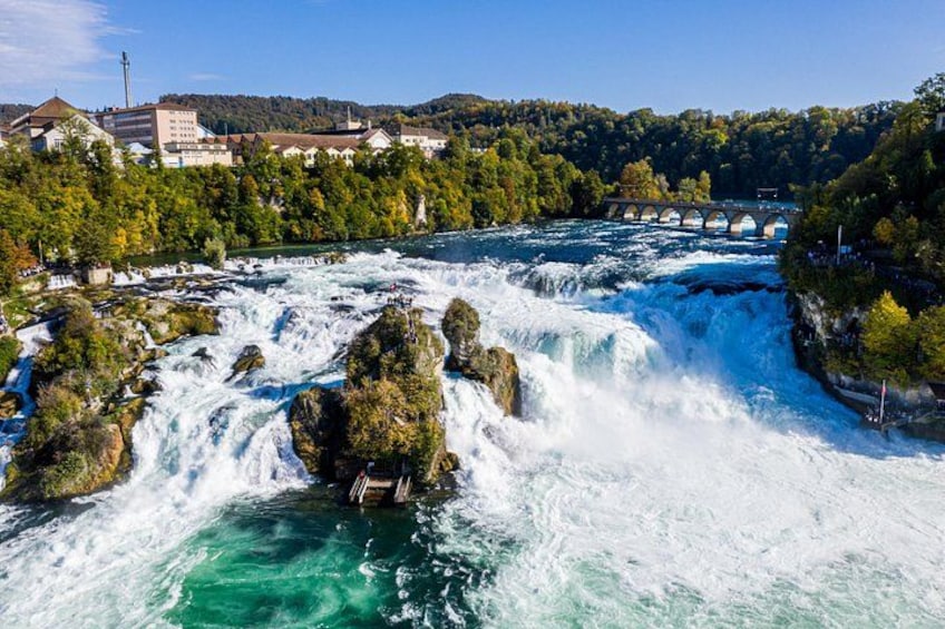 Une rivière aux eaux tumultueuses, un pont et une végétation luxuriante environnante. 1