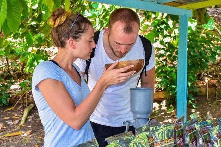 Two people examining a food item under a shelter with a table of packaged goods nearby. 1