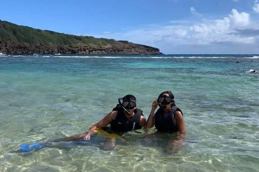 Two people snorkeling in clear water with a rocky coastline in the background. 3