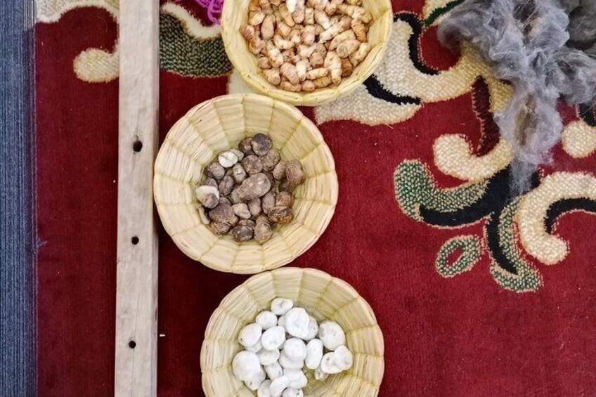 Three woven baskets on a red patterned carpet, each containing different types of nuts. 2