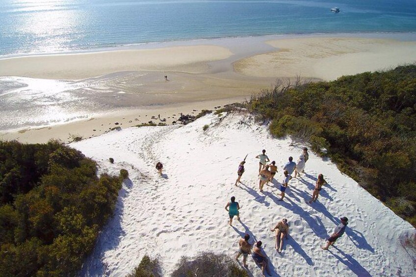 A group of people on a sandy beach with a view of the ocean and a boat in the distance. 5