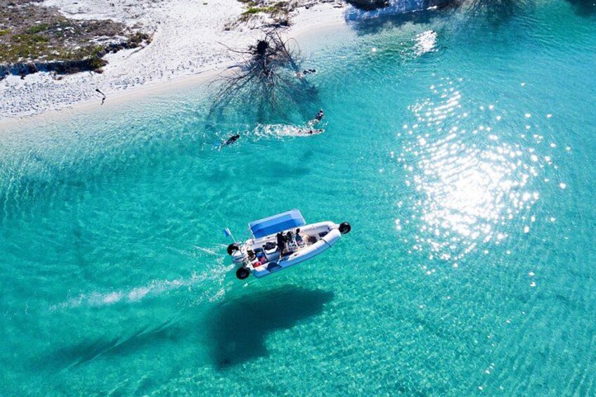A boat on turquoise water near a sandy beach with sparse vegetation. 3