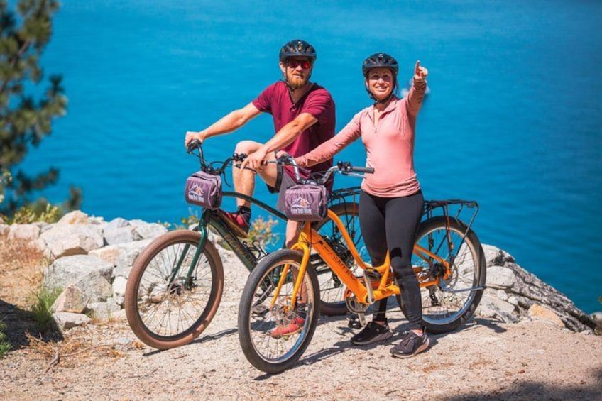 Two people on a mountain bike trail with a rocky path and a view of the sea in the background. 3