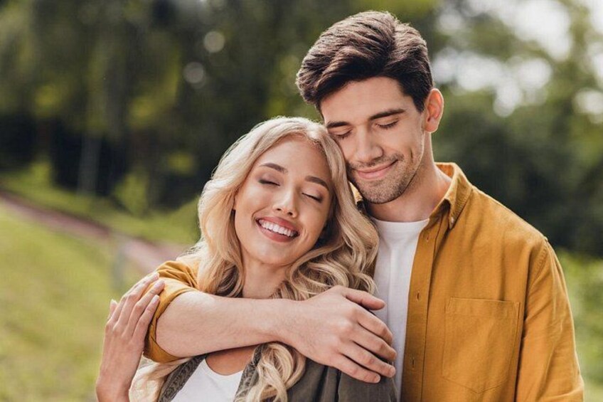 A couple embracing in a park with greenery in the background. 2