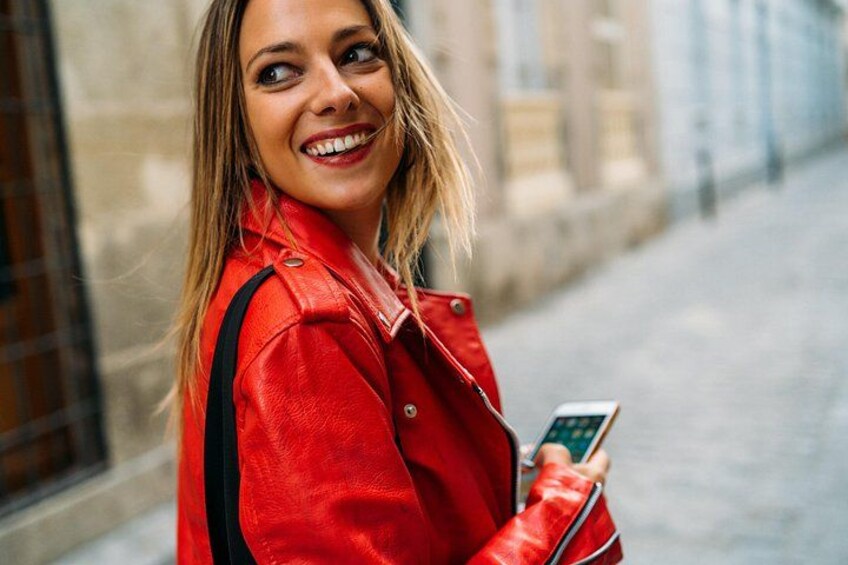 Una persona con un giubbotto rosso che tiene in mano uno smartphone. 3