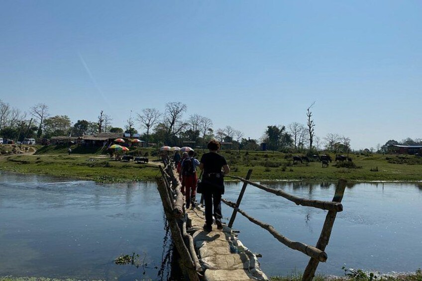 Eine Holzbrücke über einem ruhigen Fluss, Personen überqueren sie. 5