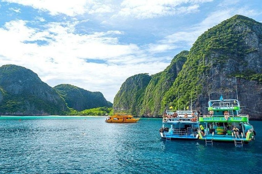 A boat with passengers, a clear blue sea, and green mountains in the background. 1