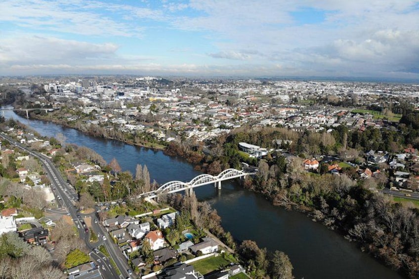 Ein Fluss fließt durch eine Stadt, gesäumt von Gebäuden und Grünflächen, mit einer Brücke. 2