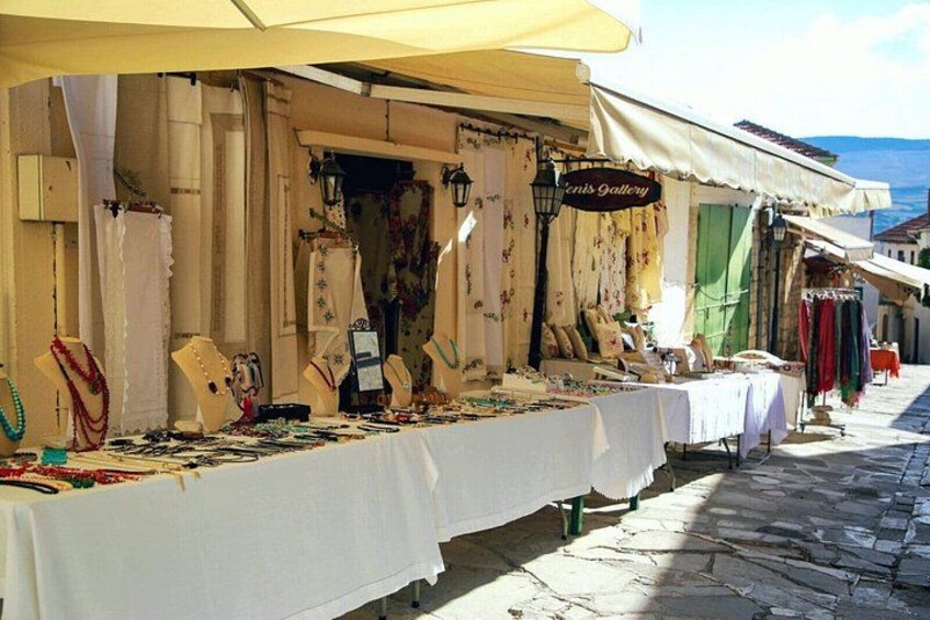 A market stall with jewelry and textiles under a tent. 2