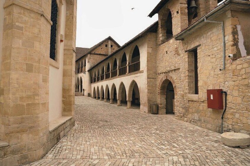 Una calle adoquinada con edificios históricos de piedra, ventanas de arco y un cuadro eléctrico rojo. 3