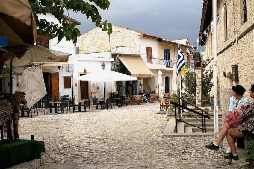 A cobblestone street with outdoor seating, buildings, and flags. 5