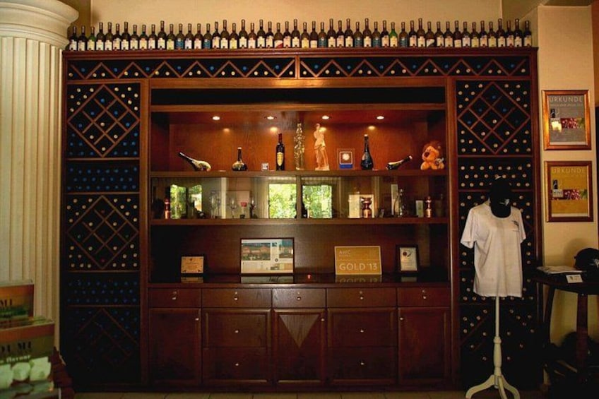 A wine cellar with wooden shelves, bottles, and a mannequin. 4
