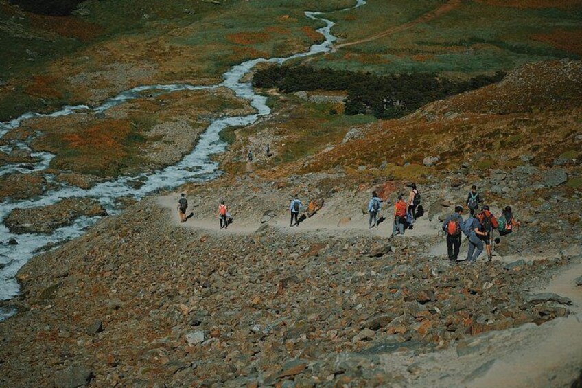 A group of hikers on a rocky terrain with a river in the background. 1